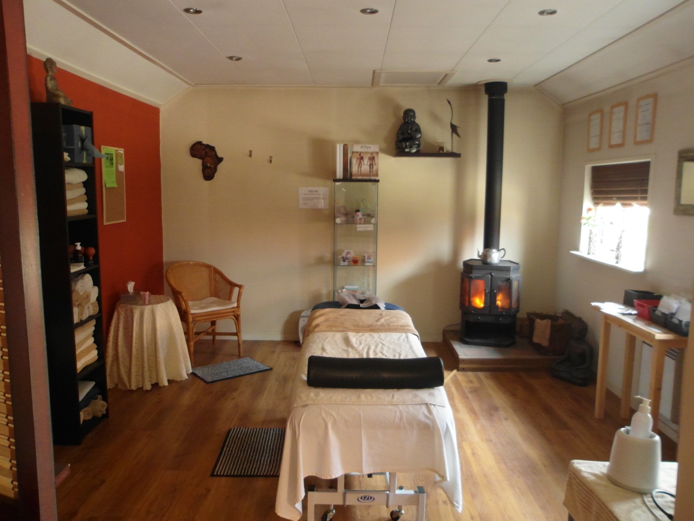 De praktijkruimte met massagetafels en houtkachel